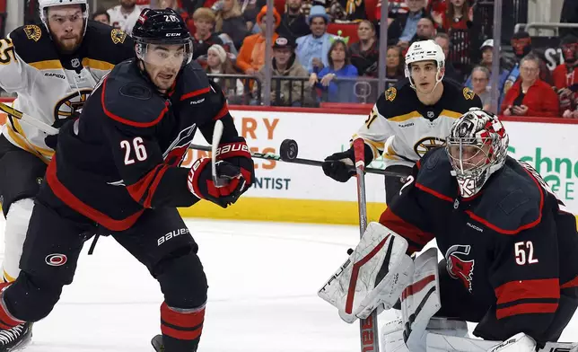 Carolina Hurricanes' Sean Walker (26) and Carolina Hurricanes goaltender Pyotr Kochetkov (52) eye the puck against the Boston Bruins during the first period of an NHL hockey game in Raleigh, N.C., Thursday, Oct. 31, 2024. (AP Photo/Karl B DeBlaker)