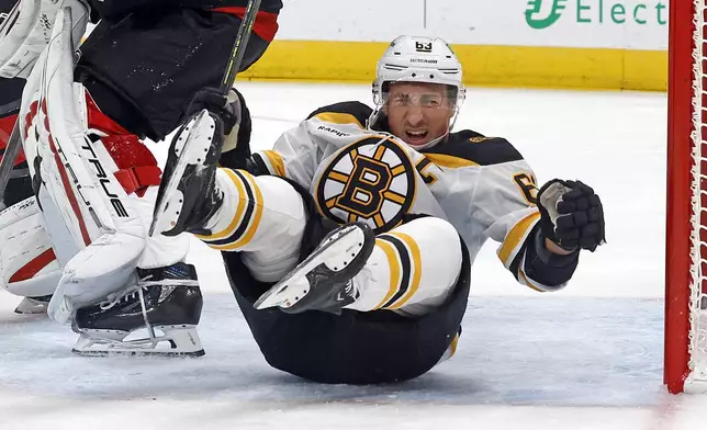 Boston Bruins' Brad Marchand (63) falls in the Carolina Hurricanes crease during the first period of an NHL hockey game in Raleigh, N.C., Thursday, Oct. 31, 2024. (AP Photo/Karl B DeBlaker)