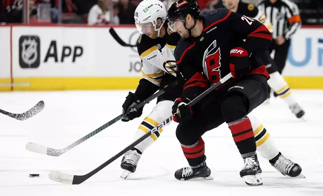 Carolina Hurricanes' Sean Walker (26) battles with Boston Bruins' Elias Lindholm (28) during the first period of an NHL hockey game in Raleigh, N.C., Thursday, Oct. 31, 2024. (AP Photo/Karl B DeBlaker)