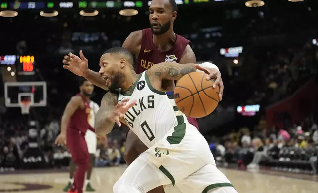 Milwaukee Bucks guard Damian Lillard (0) drives past Cleveland Cavaliers forward Evan Mobley, rear, in the second half of an NBA basketball game, Monday, Nov. 4, 2024, in Cleveland. (AP Photo/Sue Ogrocki)