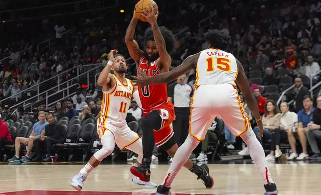 Chicago Bulls guard Coby White (0) goes between Atlanta Hawks guard Trae Young (11) and center Clint Capela (15) during the first half of an NBA basketball game Saturday, Nov. 9, 2024, in Atlanta. (AP Photo/ John Bazemore)