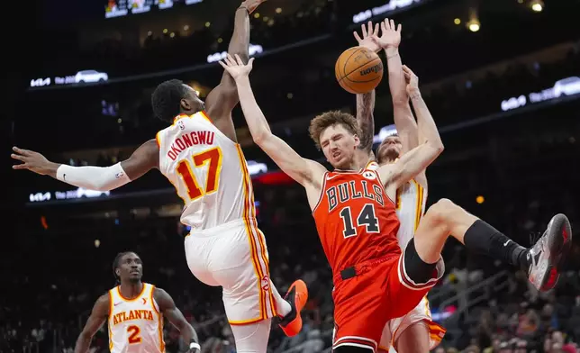 Chicago Bulls forward Matas Buzelis (14) loses control of the bll as he tries to go between Atlanta Hawks' Garrison Mathews (24) and Onyeka Okongwu (17) during the first half of an NBA basketball game Saturday, Nov. 9, 2024, in Atlanta. (AP Photo/ John Bazemore)