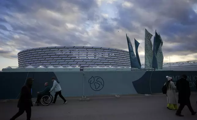 People walk outside the Baku Olympic Stadium, the venue for the COP29 U.N. Climate Summit, Wednesday, Nov. 13, 2024, in Baku, Azerbaijan. (AP Photo/Peter Dejong)