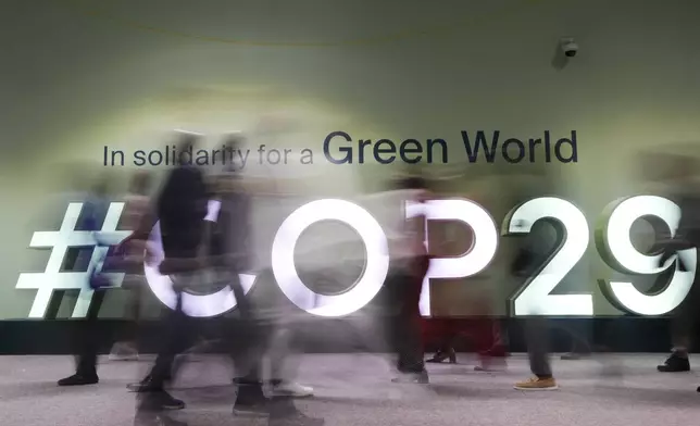 People walk through the COP29 U.N. Climate Summit, Wednesday, Nov. 13, 2024, in Baku, Azerbaijan. (AP Photo/Rafiq Maqbool)