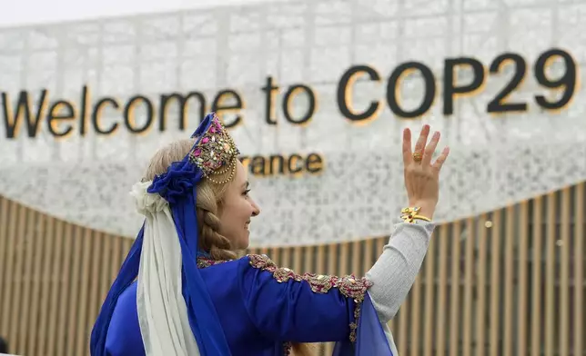 A women demonstrates with a sign on veganism at the COP29 U.N. Climate Summit, Tuesday, Nov. 12, 2024, in Baku, Azerbaijan. (AP Photo/Peter Dejong)