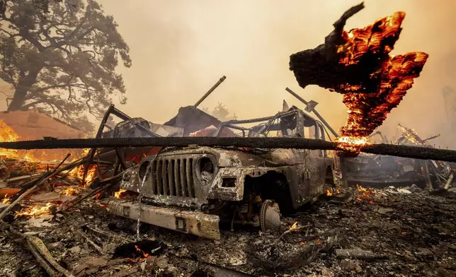 A burned vehicle sits among a destroyed home in the Mountain fire, Wednesday, Nov. 6, 2024, near Camarillo, Calif. (AP Photo/Ethan Swope)