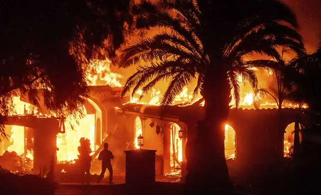 Television reporters film as flames from the Mountain Fire consume a home in Camarillo, Calif., on Wednesday, Nov. 6, 2024. (AP Photo/Noah Berger)