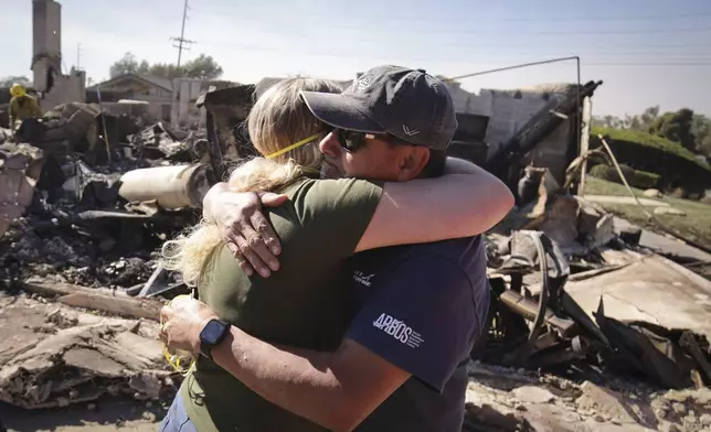 Kelly Barton, left, is hugged by a family friend after arriving at her parents' fire-ravaged property in the aftermath of the Mountain Fire, Thursday, Nov. 7, 2024, in Camarillo, Calif. (AP Photo/Ethan Swope)