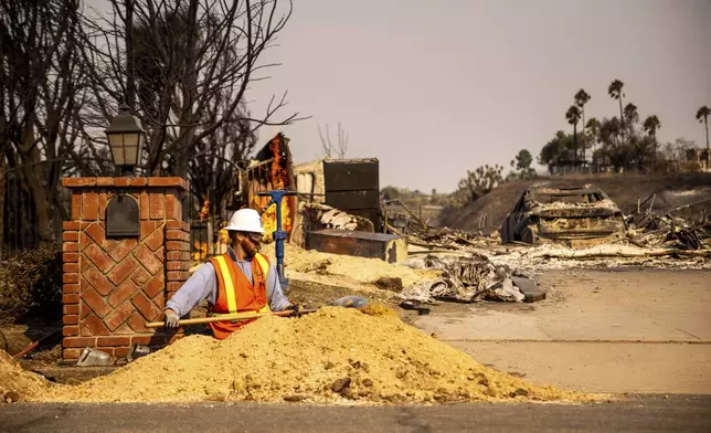 A worker digs a trench in front of a fire-ravaged property after the Mountain Fire swept through, Thursday, Nov. 7, 2024, in Camarillo, Calif. (AP Photo/Ethan Swope)