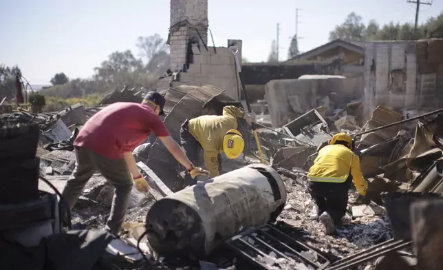 Todd Howard, left, sifts through the remains of his parents' fire-ravaged property with the help of firefighters after the Mountain Fire swept through, Thursday, Nov. 7, 2024, in Camarillo, Calif. (AP Photo/Ethan Swope)