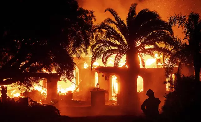 A firefighter watches as flames from the Mountain Fire consume a home in Camarillo, Calif., on Wednesday, Nov. 6, 2024. (AP Photo/Noah Berger)