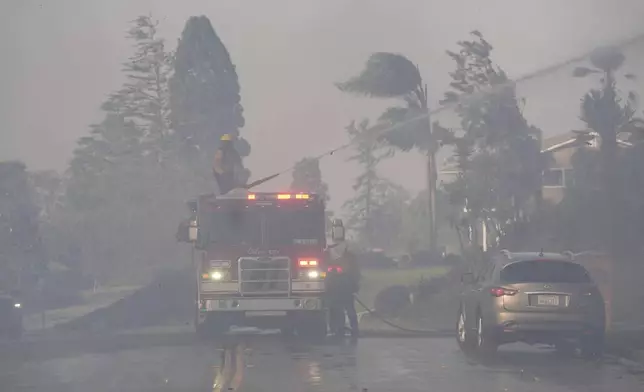 Firefighters work through heavy winds and smoke in the Mountain fire, Wednesday, Nov. 6, 2024, in Camarillo, Calif. (AP Photo/Marcio Jose Sanchez)