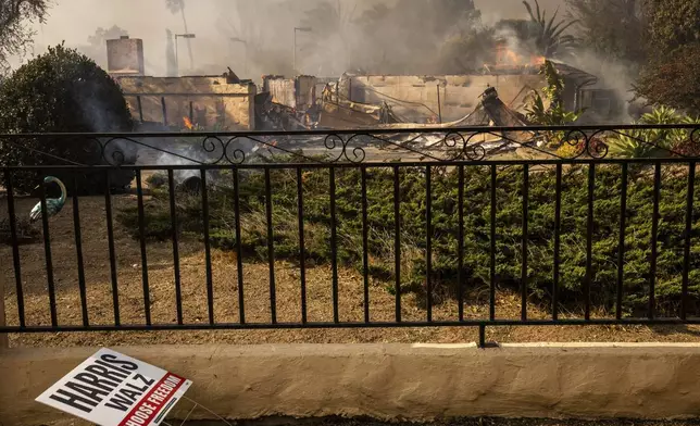 A political sign sits in front of a destroyed home in the Mountain fire, Wednesday, Nov. 6, 2024, near Camarillo, Calif. (AP Photo/Ethan Swope)