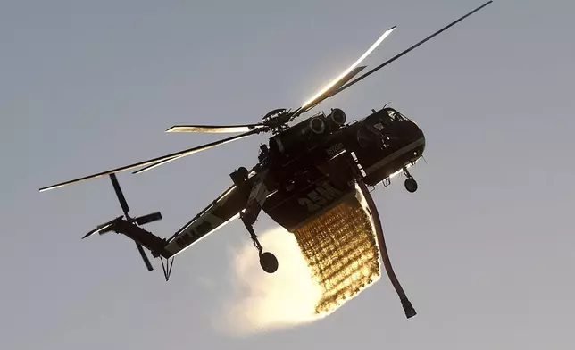 A helicopter drops water while battling the Mountain Fire along Waters Road in Moorpark, Calif., on Thursday, Nov. 7, 2024. (AP Photo/Noah Berger)