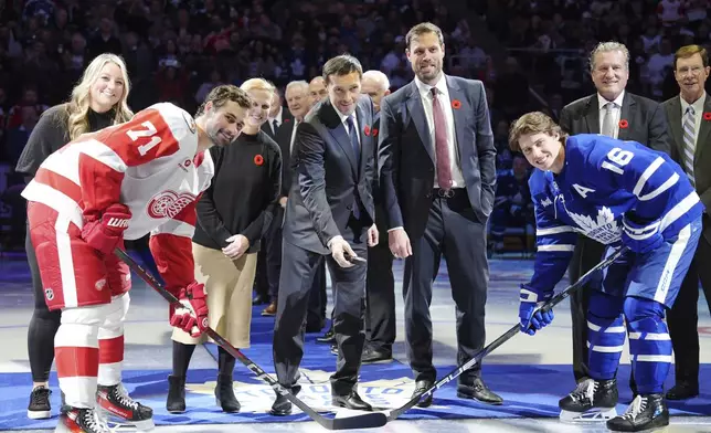 2024 Hockey Hall of Fame inductees Krissy Wendell-Pohl, back left to right, Natalie Darwitz, Pavel Datsyuk, Shea Weber, Jeremy Roenick and David Poile pose for a ceremonial face-off photo with Detroit Red Wings' Dylan Larkin (71) and Toronto Maple Leafs' Mitch Marner (16) during a pre-game ceremony prior to NHL hockey action in Toronto on Friday, November 8, 2024. (Frank Gunn/The Canadian Press via AP)