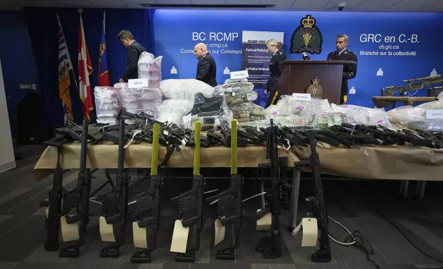 Firearms and illicit drugs seized last week are displayed as Royal Canadian Mounted Police Chief Supt. Stephen Lee, back from left, Asst. Commissioner David Teboul, Insp. Jillian Wellard and Cpl. Arash Seyed leave after a news conference at RCMP headquarters, in Surrey, British Columbia, Thursday, Oct. 31, 2024. The RCMP says they have dismantled "the largest and most sophisticated fentanyl and methamphetamine drug superlab in Canada," after an operation was conducted in Falkland, British Columbia, and Surrey beginning last Friday. (Darryl Dyck/The Canadian Press via AP)