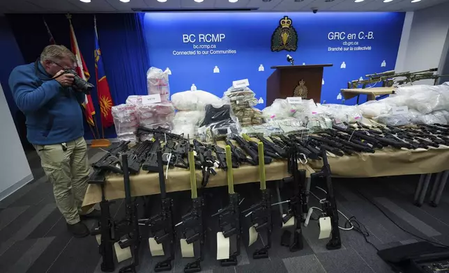 Firearms, illicit drugs and cash that were seized last week are displayed before a news conference at Royal Canadian Mounted Police headquarters, in Surrey, British Columbia, Thursday, Oct. 31, 2024. (Darryl Dyck/The Canadian Press via AP)