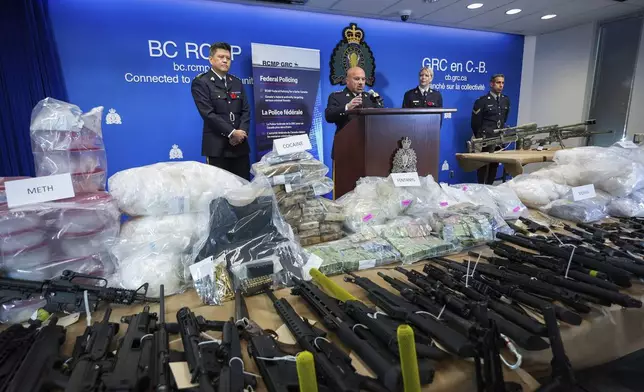 Firearms and illicit drugs seized last week are displayed as Royal Canadian Mounted Police Chief Supt. Stephen Lee, from left, Asst. Commissioner David Teboul, Insp. Jillian Wellard and Cpl. Arash Seyed attend a news conference at RCMP headquarters, in Surrey, British Columbia, Thursday, Oct. 31, 2024. (Darryl Dyck/The Canadian Press via AP)