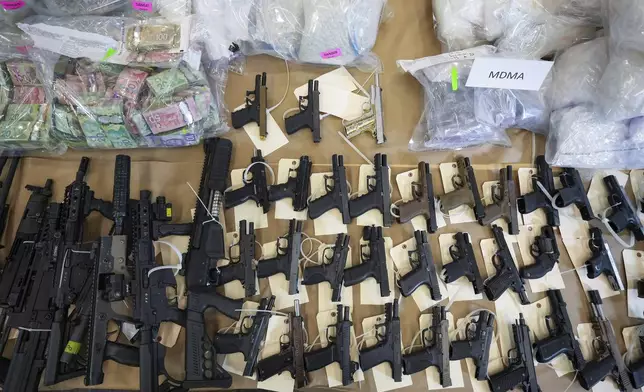 Firearms, illicit drugs and cash that were seized last week are displayed before a news conference at Royal Canadian Mounted Police headquarters, in Surrey, British Columbia, Thursday, Oct. 31, 2024. (Darryl Dyck/The Canadian Press via AP)