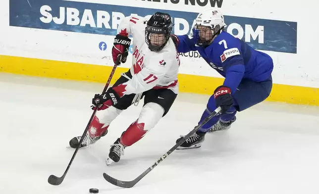 Canada defense Ella Shelton (17) battles for the puck against U.S. forward Lacey Eden (7) during the first period of a women's Rivalry Series hockey game in San Jose, Calif., Wednesday, Nov. 6, 2024. (AP Photo/Tony Avelar)