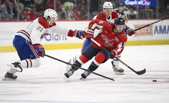 Washington Capitals left wing Andrew Mangiapane (88) skates with the puck against Montreal Canadiens defenseman Kaiden Guhle (21) and center Christian Dvorak (28) during the first period of an NHL hockey game, Thursday, Oct. 31, 2024, in Washington. (AP Photo/Nick Wass)