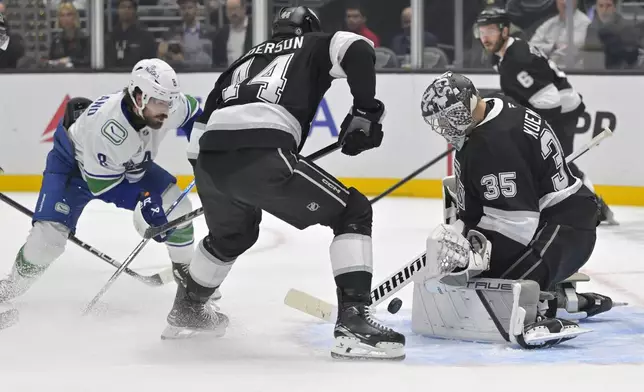 Los Angeles Kings goaltender Darcy Kuemper, right, blocks a shot by Vancouver Canucks right wing Conor Garland as Los Angeles Kings defenseman Mikey Anderson (44) watches during the first period of an NHL hockey game, Thursday, Nov. 7, 2024, in Los Angeles. (AP Photo/Jayne-Kamin-Oncea)