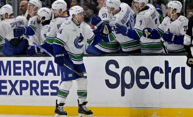 Vancouver Canucks left wing Jake DeBrusk (74) in congratulated by teammates after scoring a goal during the second period of an NHL hockey game against the Los Angeles Kings, Thursday, Nov. 7, 2024, in Los Angeles. (AP Photo/Jayne-Kamin-Oncea)