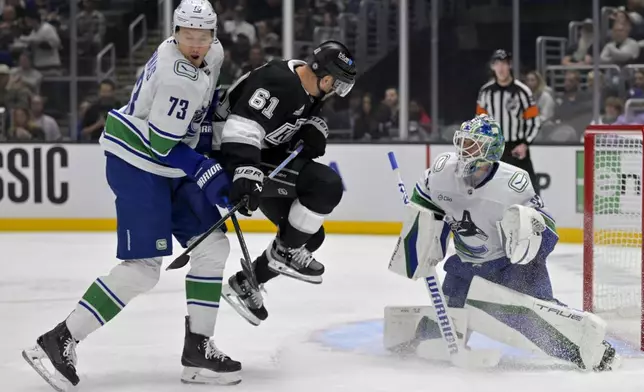 Los Angeles Kings center Trevor Lewis (61) jumps out of the way of a shot on goal in front of Vancouver Canucks defenseman Vincent Desharnais, left, as Canucks goaltender Kevin Lankinen (32) looks on during the second period of an NHL hockey game, Thursday, Nov. 7, 2024, in Los Angeles. (AP Photo/Jayne-Kamin-Oncea)