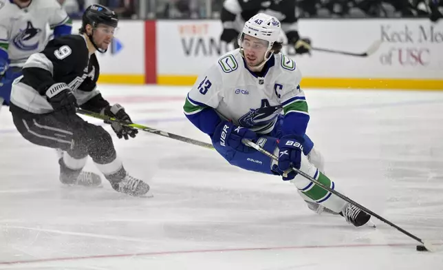 Vancouver Canucks defenseman Quinn Hughes handles the puck in front of Los Angeles Kings right wing Adrian Kempe (9) during the second period of an NHL hockey game, Thursday, Nov. 7, 2024, in Los Angeles. (AP Photo/Jayne-Kamin-Oncea)