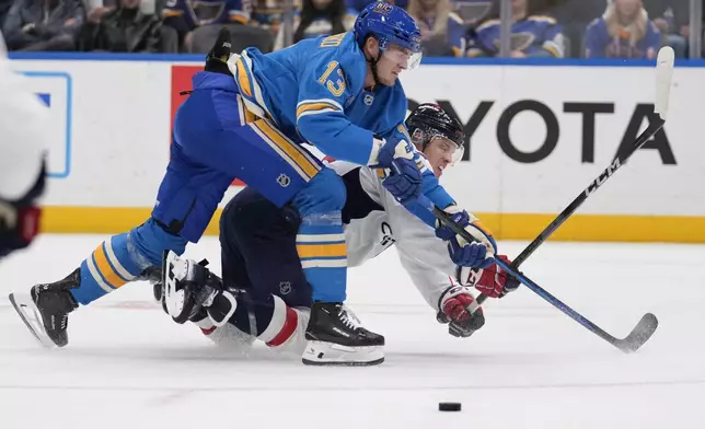 St. Louis Blues' Alexey Toropchenko (13) and Washington Capitals' John Carlson battle for a loose puck during the second period of an NHL hockey game Saturday, Nov. 9, 2024, in St. Louis. (AP Photo/Jeff Roberson)