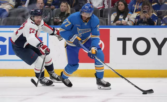 St. Louis Blues' Pierre-Olivier Joseph (77) handles the puck as Washington Capitals' Brandon Duhaime (22) during the first period of an NHL hockey game Saturday, Nov. 9, 2024, in St. Louis. (AP Photo/Jeff Roberson)