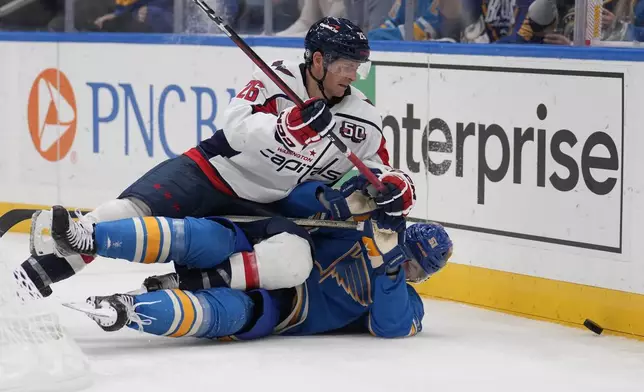 Washington Capitals' Nic Dowd (26) and St. Louis Blues' Matthew Kessel battle for a loose puck along the boards during the third period of an NHL hockey game Saturday, Nov. 9, 2024, in St. Louis. (AP Photo/Jeff Roberson)