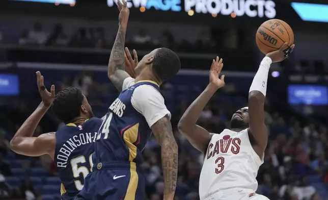 Cleveland Cavaliers guard Caris LeVert (3) shoots against New Orleans Pelicans guard Jordan Hawkins (24) and forward Jeremiah Robinson-Earl (50) in the first half of an NBA basketball game in New Orleans, Wednesday, Nov. 6, 2024. (AP Photo/Gerald Herbert)