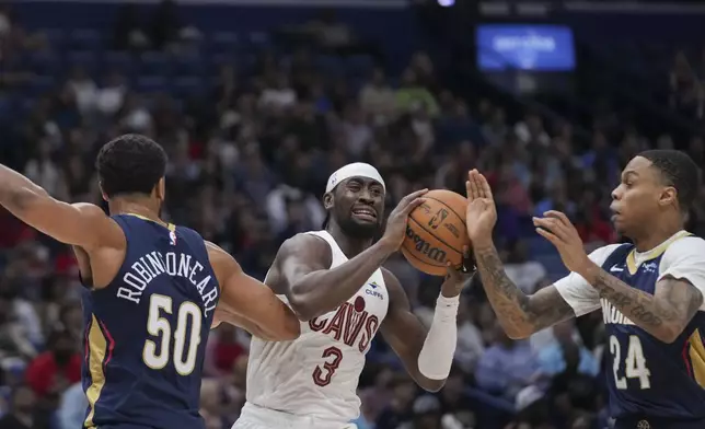 Cleveland Cavaliers guard Caris LeVert (3) battles between New Orleans Pelicans forward Jeremiah Robinson-Earl (50) and guard Jordan Hawkins (24) in the first half of an NBA basketball game in New Orleans, Wednesday, Nov. 6, 2024. (AP Photo/Gerald Herbert)