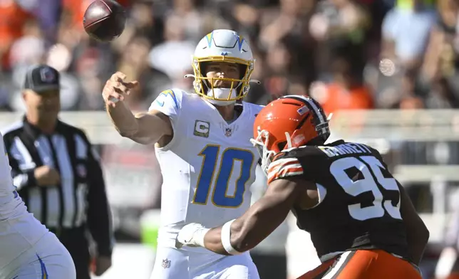 Los Angeles Chargers quarterback Justin Herbert (10) passes over Cleveland Browns defensive end Myles Garrett (95) in the first half of an NFL football game Sunday, Nov. 3, 2024, in Cleveland. (AP Photo/David Richard)