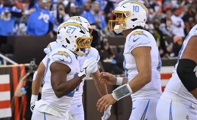 Los Angeles Chargers running back J.K. Dobbins (27) celebrates with quarterback Justin Herbert (10) after Dobbins ran for a touchdown against the Cleveland Browns in the first half of an NFL football game Sunday, Nov. 3, 2024, in Cleveland. (AP Photo/David Richard)