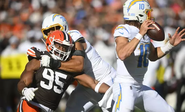 Los Angeles Chargers offensive tackle Rashawn Slater (70) keeps Cleveland Browns defensive end Myles Garrett (95) away from Chargers' quarterback Justin Herbert (10) in the first half of an NFL football game Sunday, Nov. 3, 2024, in Cleveland. (AP Photo/David Richard)