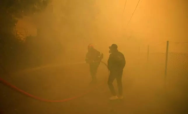 FILE - A firefighter and volunteer try to extinguish a wildfire in northern Athens, Aug. 12, 2024, as firefighters tackle a wildfire. (AP Photo/Michael Varaklas, File)