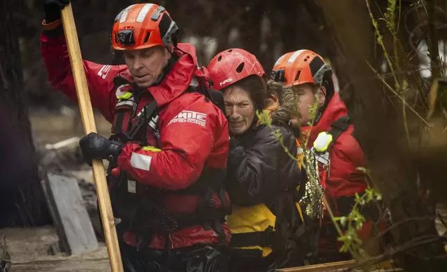 FILE - Firefighters rescue a woman from a homeless encampment that became surrounded by floodwater in the Santa Ana River during a rainstorm, Feb. 5, 2024, in San Bernardino, Calif. (AP Photo/Ethan Swope, File)