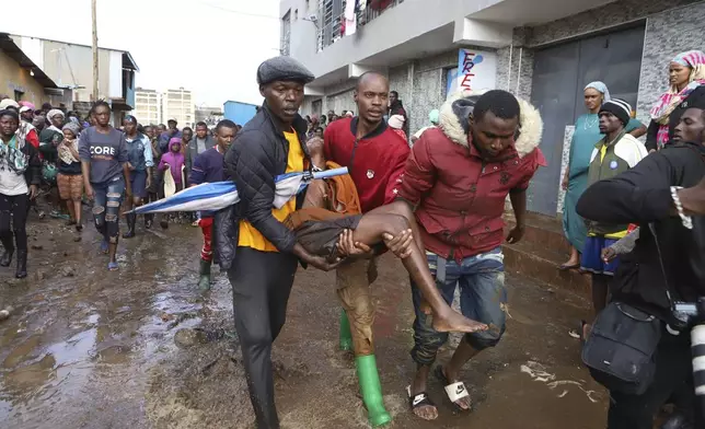 FILE - Residents rescue a woman who was caught during heavy rain in the Mathare slum of Nairobi, Kenya, Apr. 24, 2024. (AP Photo/Andrew Kasuku, File)