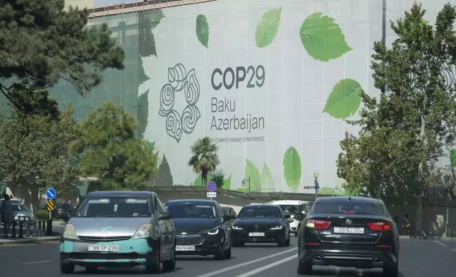 Vehicles drive near a sign for COP29, the United Nations Climate Change Conference, in Baku, Azerbaijan, Monday, Sept. 16, 2024. (AP Photo/Sergei Grits)