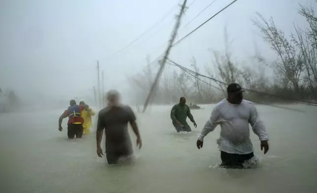 FILE - Volunteers wade through a flooded road in the aftermath of Hurricane Dorian to rescue families near the Causarina bridge in Freeport, Grand Bahama, Bahamas, on Sept. 3, 2019. (AP Photo/Ramon Espinosa)