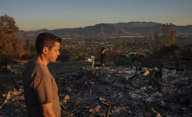 Louie Gonzalez, foreground, and his mother, Kathy, background center, visit Kathy's home devastated in the Mountain Fire in Camarillo, Calif., Nov. 8, 2024. (AP Photo/Jae C. Hong)