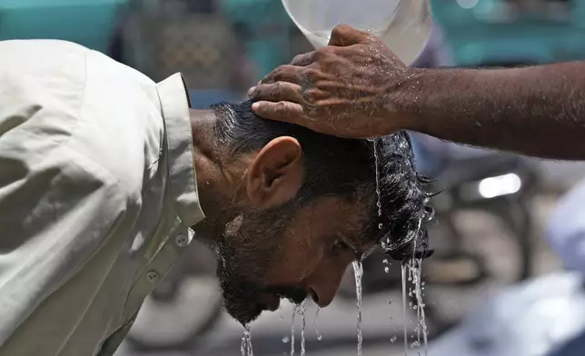 FILE - A volunteer pours water to cool a man off during a hot day in Karachi, Pakistan, May 21, 2024. (AP Photo/Fareed Khan, File)