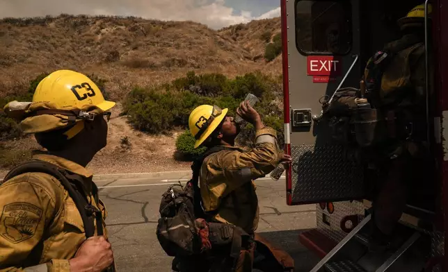 FILE - Firefighter Geo Mulongo, center, finishes his water while taking a break during the Line Fire in Highland, Calif., Sept. 6, 2024. (AP Photo/Jae C. Hong, File)