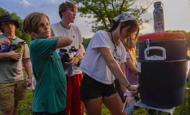 FILE - Counselor Izzy Kellar, of Dayton, Ohio, fills up her campers' water bottles, June 20, 2024, at YMCA Camp Kern in Oregonia, Ohio. (AP Photo/Joshua A. Bickel)