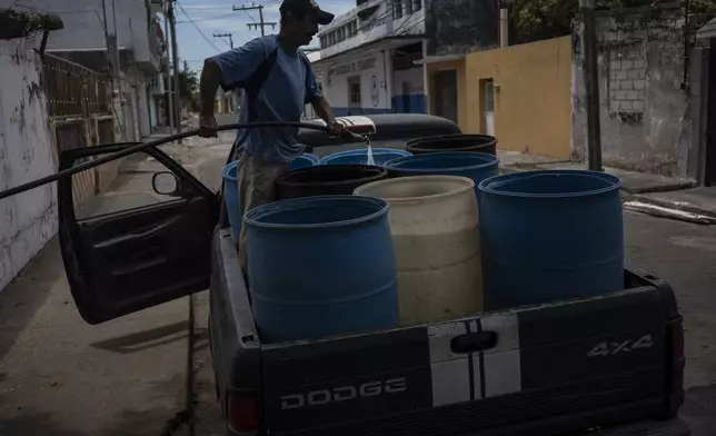 FILE - A man fills containers with water due to the shortage caused by high temperatures and drought in Veracruz, Mexico, on June 16, 2024. (AP Photo/Felix Marquez, File)