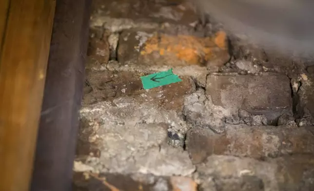 A dog's paw print (left of arrow) is seen in one of the chimney bricks at the Bray School on Wednesday, Oct 30, 2024 in Williamsburg, Va. (AP Photo/John C. Clark)