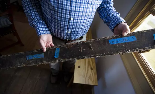 Matthew Webster shows an original rail from the classroom of the Williamsburg Bray School on Wednesday, Oct 30, 2024 in Williamsburg, Va. (AP Photo/John C. Clark)