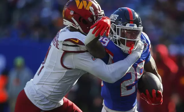 New York Giants running back Tyrone Tracy Jr. (29) tries to break a tackle by Washington Commanders cornerback Noah Igbinoghene (1) during the second quarter of an NFL football game, Sunday, Nov. 3, 2024, in East Rutherford, N.J. (AP Photo/John Munson)